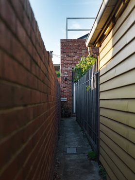 Narrow walkway between buildings to enter Gezellig House. Photography by Trevor Mein