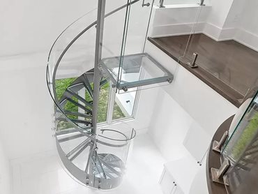 The extensive use of glass in the staircase’s railing and treads allows natural light to penetrate deep into the room