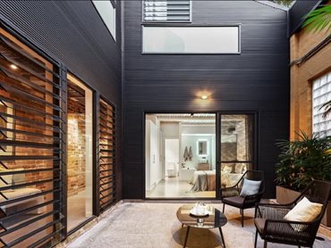 The juxtaposition of the glass and aluminium louvres, exposed brick walls, polished concrete floors, and sleek finishes create a striking visual contrast