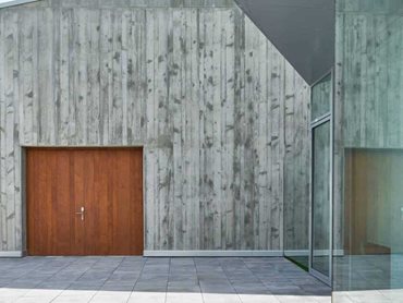 The natural wood panels are configured vertically to harmonise with the concrete